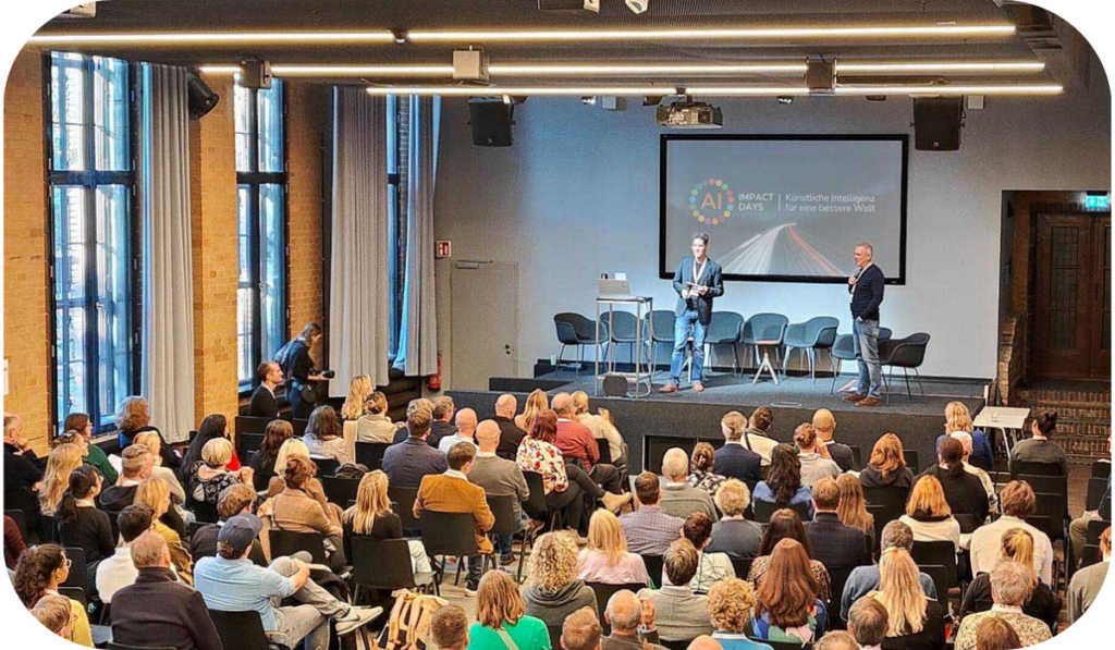 ai-impact-event-menge Ai Impact Event 2025 volle Halle mit Publikum vor großer Bühne mit Moderation